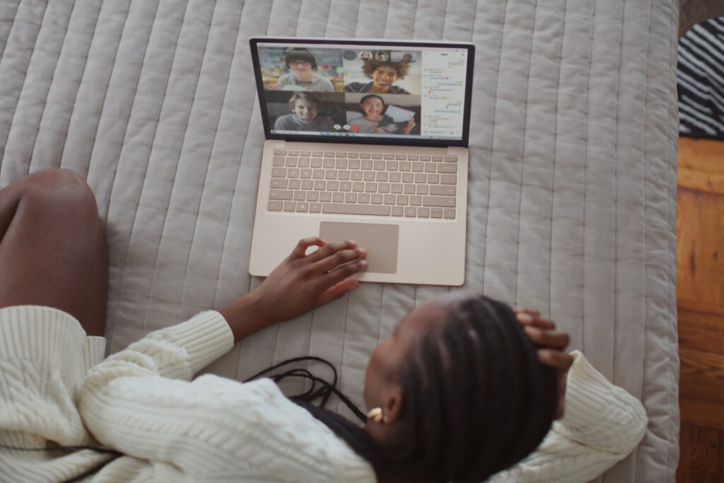 A person laying on a bed taking part in a remote meeting.